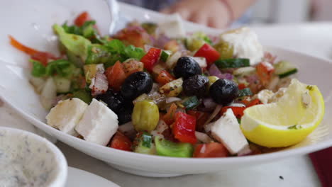 Person-Eating-A-Fresh-Dish-Of-Greek-Salad-At-A-Restaurant-Table,-Close-Up-Shot