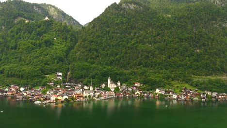 Aerial-view-of-Hallstatt,-Austria,-captured-by-drone,-showcasing-its-picturesque-lakeside-homes,-majestic-mountains,-and-the-unique-charm-of-this-enchanting-alpine-village