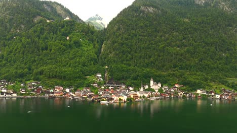 Aerial-view-of-Hallstatt,-Austria,-captured-by-drone,-showcasing-its-picturesque-lakeside-homes,-majestic-mountains,-and-the-unique-charm-of-this-enchanting-alpine-village