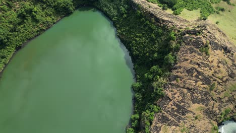 Aerial-view-of-Lac-Niamawi's-volcanic-crater-lake-surrounded-by-lush-green-foliage