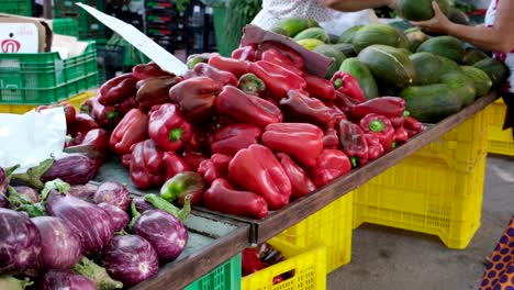 Unrecognizable-people-are-shopping-at-the-Saturday-market-with-displays-of-abundant-red-bell-peppers-and-watermelon