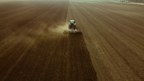 Tractor-operates-across-broad-semi-dry-land,-drone-shot