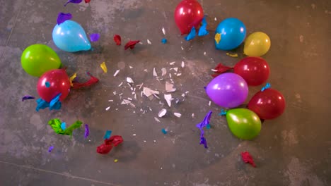 A-plate-being-dropped-in-the-middle-of-colorful-balloons-and-it-breaks-in-pieces-and-the-bits-and-shards-shatter-and-make-balloons-explode-around-it-in-slow-motion