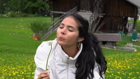 Happy-glowing-female-blows-dandelion-in-green-meadow,-static-portrait-view