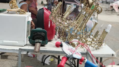 A-vintage,-gold-colored-metallic-chandelier,-along-with-other-antique-items,-is-elegantly-displayed-at-the-flea-market,-attracting-attention-with-its-timeless-charm-and-character