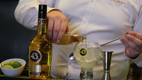 Ein-Mann-Bereitet-Gekonnt-Cocktails-Mit-Licor-43-Zu,-Einem-Berühmten-Spanischen-Likör,-Und-Stellt-Seine-Lebendigen-Aromen-In-Einer-Fesselnden-Präsentation-Einem-Gespannten-Publikum-Vor