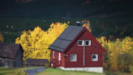 A-small-red-wooden-cabin-stands-in-the-autumn-landscape-at-the-foot-of-the-mountain