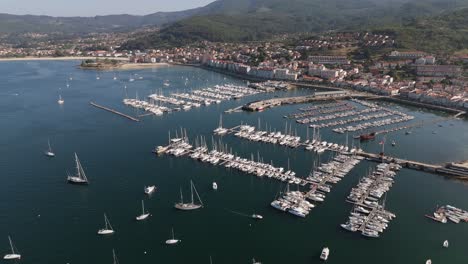 Aerial-view-of-Baiona's-marina,-showing-moored-boats-and-the-town's-coastline-in-Spain