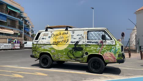 A-vibrant,-multicolored-old-Churros-vehicle-is-parked-in-front-of-a-residential-building,-adding-a-nostalgic-and-lively-touch-to-the-urban-scene