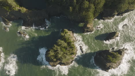 Smooth-drone-shot-gliding-through-the-rocky-natural-bridges-of-the-Oregon-coast,-with-waves-crashing-through-the-formations