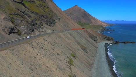 Este-Impresionante-Video-Con-Dron-Captura-El-Fascinante-Contraste-Entre-El-Azul-Profundo-Del-Océano-Y-Los-Imponentes-Picos-De-Las-Montañas,-Resaltando-El-Espectacular-Y-Diverso-Paisaje-De-Islandia.