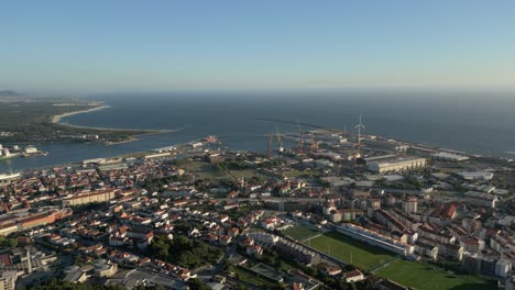 Coastal-cityscape-Viana-do-Casteçp-overlooking-river,-ocean,-and-industrial-port-with-wind-turbines