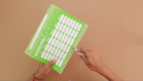 Punching-holes-in-school-schedule-planner-with-professional-tool,-paper-arts-and-crafts