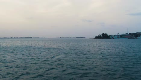 Aerial-over-calm-water-at-San-Bay-with-boats-and-an-overcast-sky-in-the-distance