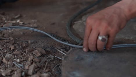 Hands-working-with-cables-on-a-dusty-ground,-focus-on-manual-labor-and-craftsmanship