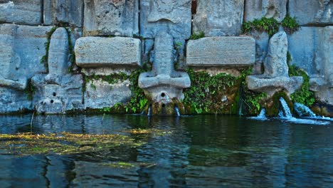 The-ancient-stone-carvings-of-the-Holy-Water-Temple,-where-water-flows-gently-from-the-statues