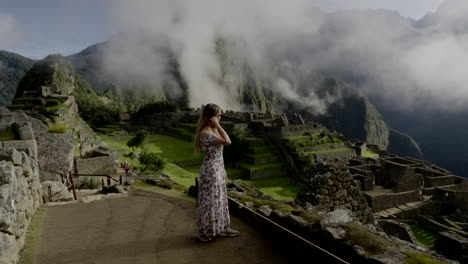 Tourist-woman-in-dress-inside-Machu-Picchu-lost-city-watches-landscape