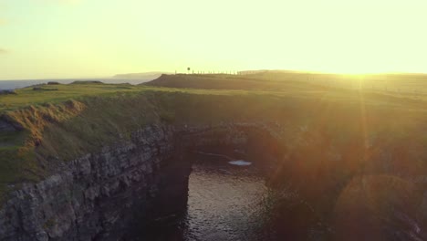 Aerial-reverse-dolly-and-ascent-reveals-the-Bridges-of-Ross-and-surrounding-landscape-bathed-in-sunrise-light