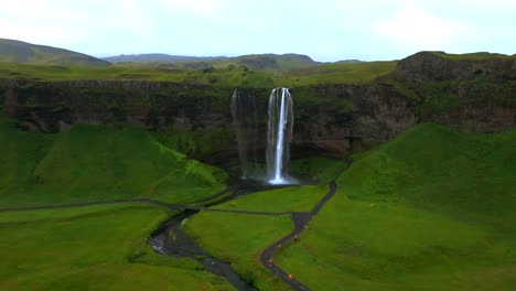 Entdecken-Sie-Die-Verborgene-Schönheit-Des-Seljalandsfoss-Aus-Der-Luft,-Wo-Der-Nebel-Des-Wasserfalls-Im-Sonnenlicht-Tanzt