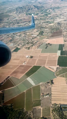 Un-Paisaje-Escénico-Se-Despliega-A-Través-De-La-Ventana-Del-Avión,-Enmarcado-Por-El-Reconocible-Logotipo-De-Ryanair-En-El-Ala,-Capturando-La-Esencia-De-Un-Viaje-En-Pleno-Vuelo-Sobre-Un-Terreno-Distante.