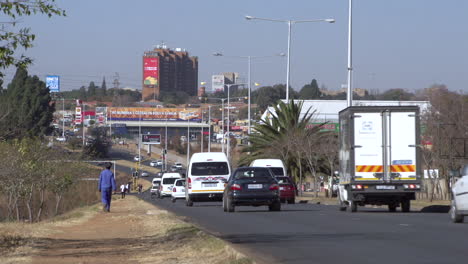 Los-Automóviles-De-Pasajeros-Y-Los-Taxis-Circulan-Por-Una-Ruta-Principal-En-El-Municipio-De-Soweto,-En-Johannesburgo,-Sudáfrica.