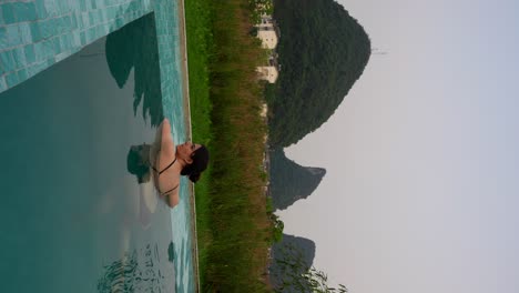 Woman-bathing-in-pool-at-sunset-with-karst-mountain-views-in-Yangshuo,-China