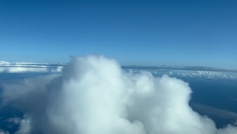 Immersive-pilot’s-POV-FPV-flying-over-the-top-of-a-cottony-cloud-in-a-blue-sky-in-a-sunny-day