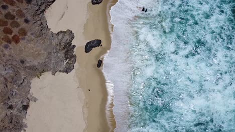 Clear-turquoise-blue-water-waves-crashing-on-rocky-white-sandy-beach