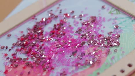 Pink-sequins-in-swirl-and-stars-shape-falling-on-a-pile,-close-up