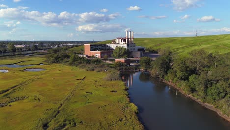 An-aerial-view-of-marsh-water-with-an-abandoned-waste-processing-plant,-taken-on-a-sunny-day-on-Long-Island,-New-York