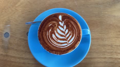 Cappuccino-coffee-latte-art,-blue-mug-caffeine-drink-with-milk,-wooden-table-artisan-shop