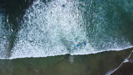 Surfers-surfing-on-surfboards-in-clear-turquoise-shallow-water-at-popular-vacation-spot