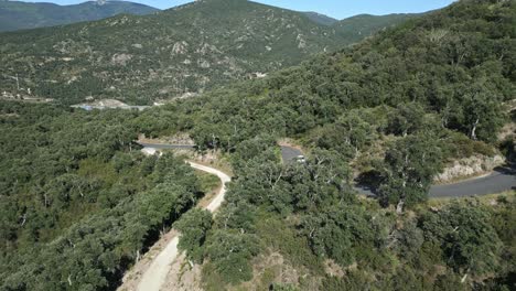 Drone-follows-white-car-driving-through-Pyrenees-Green-Summer-Mountains,-Aerial-view