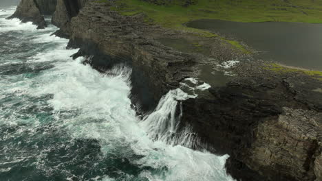 Aerial-high-angle-shot-of-Lake-Sorvágsvatn-waterfall-falling-into-sea,-Faroe-Islands