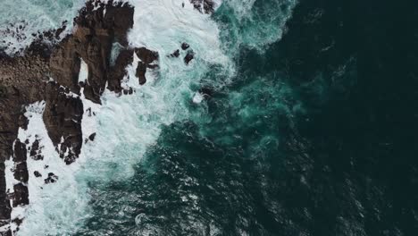 Aerial-birds-eye-view-showcasing-powerful-ocean-waves-crashing-against-the-rocky-coastline-at-Playa-Chica,-Quintay-in-Valparaíso,-Chile