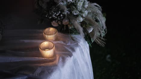 Candles-glow-next-to-delicate-flower-bouquet-at-a-night-wedding-setting