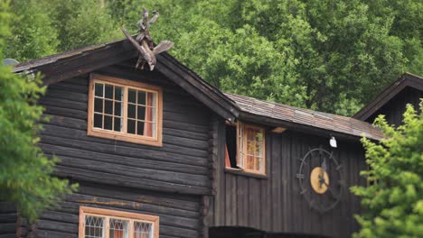 Un-Edificio-De-Madera-En-El-Complejo-Hotelero-Elveseter-Se-Encuentra-En-Medio-De-Una-Exuberante-Vegetación,-Con-Un-Exterior-Rústico-Y-Un-Reloj-Visible.