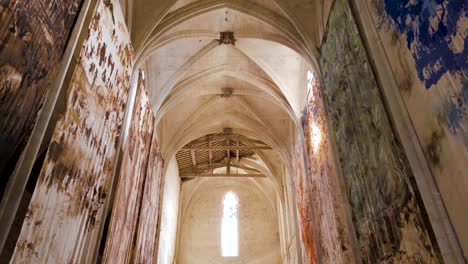 Slow-motion-shot-of-of-large-archways-and-paintings-within-a-French-Abbey