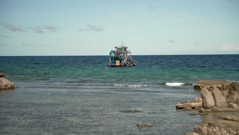 An-Einem-Ruhigen-Morgen-Liegt-Ein-Schwimmendes-Partyboot-Vor-Dem-Strand-Von-Sairee-In-Koh-Tao,-Thailand,-Vor-Anker-Und-Bietet-Einen-Blick-Auf-Eine-Ruhige-Küstenlandschaft-Und-Einladendes-Wasser