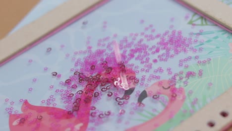 Pink-sequins-falling-on-top-of-hand-made-notebook,-close-up