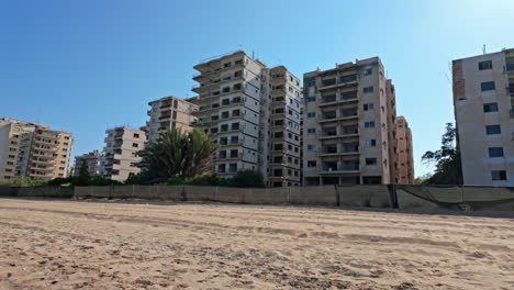 Abandoned-beachfront-high-rise-buildings-under-a-clear-blue-sky-with-sand-in-the-foreground