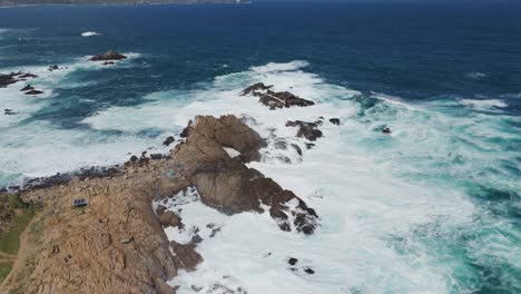 Aerial-view-of-turquoise-waves-crashing-on-rocks-on-the-chilean-coast-at-playa-chica-near-valparaiso