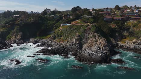 Aerial-view-of-charming-cliff-top-homes-overlooking-the-Pacific-Ocean-in-Caleta-Quintay,-Casablanca,-Valparaíso,-Chile