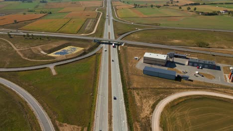 Drone-shot-of-expressway-highway-road-traffic-through-agricultural-fields,-Highway-road-service-zone-area