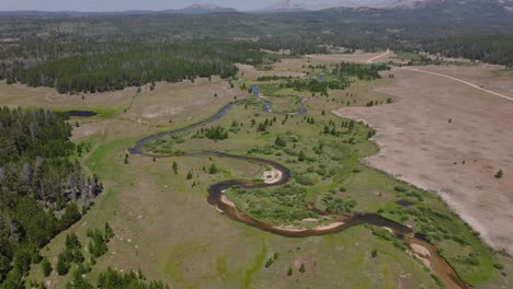 Luftaufnahme-Des-Mäandernden-Flusses-Am-Großen-Sandigen-Ausgangspunkt-In-Der-Wildnis-Des-Wind-River,-Wyoming,-Mit-Weiten-Grünen-Ebenen-Und-Bergigem-Gelände