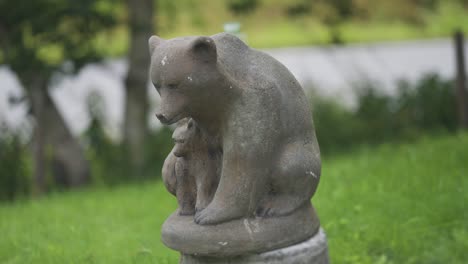 The-statue-of-the-mother-bear-and-her-cub-in-the-park-surrounded-by-lush-grass-and-trees