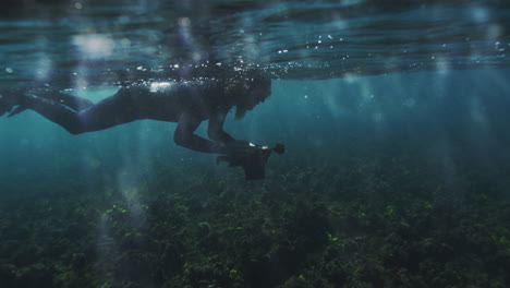 Fotograf-Schwimmt-Auf-Der-Oberfläche-Des-Ozeans-Balancieren-Kamera-Nach-Unten-Gerichtet,-Während-Die-Gleiten-Durch-Glitzernden-Blendenden-Offenen-Wasser