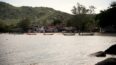 Several-colorful-longtail-boats-are-moored-near-the-shore-of-a-tropical-island-in-thailand