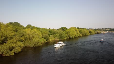 A-River-Boat-and-Narrow-Boat-pass-each-other-in-opposite-directions-on-a-sunny,-summers-day-on-the-River-Trent-in-the-Nottinghamshire-countryside