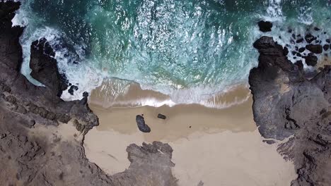 Waves-crashing-on-white-sand-beach-with-rocky-coastline-with-clear-turquoise-water